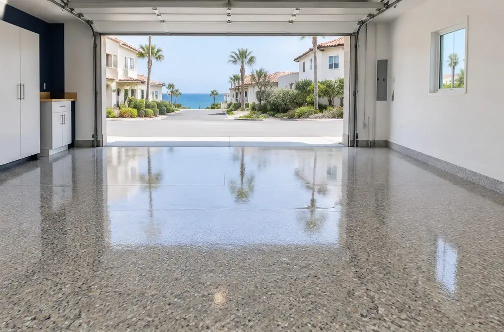 Illustration: a finished garage floor with a gray-and-tan flake coating and a glossy clear top coat reflecting the open door